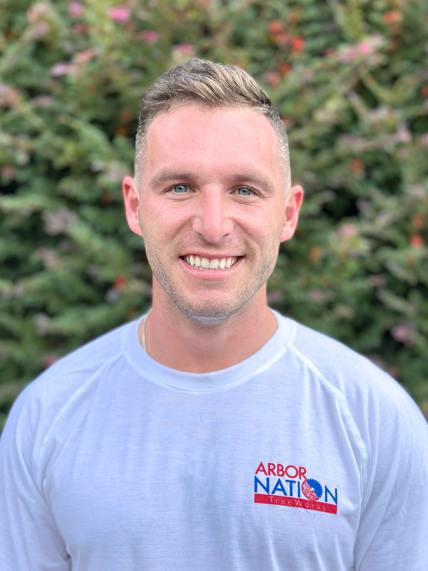 Man wearing a gray shirt with Arbor Nation logo against a blurred green background