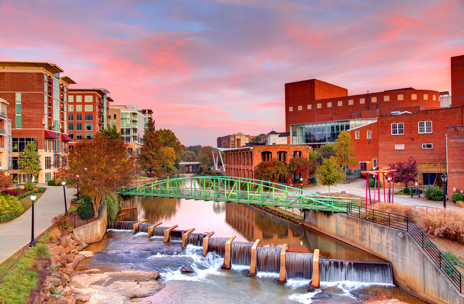 Cityscape with a canal and green bridge at sunset