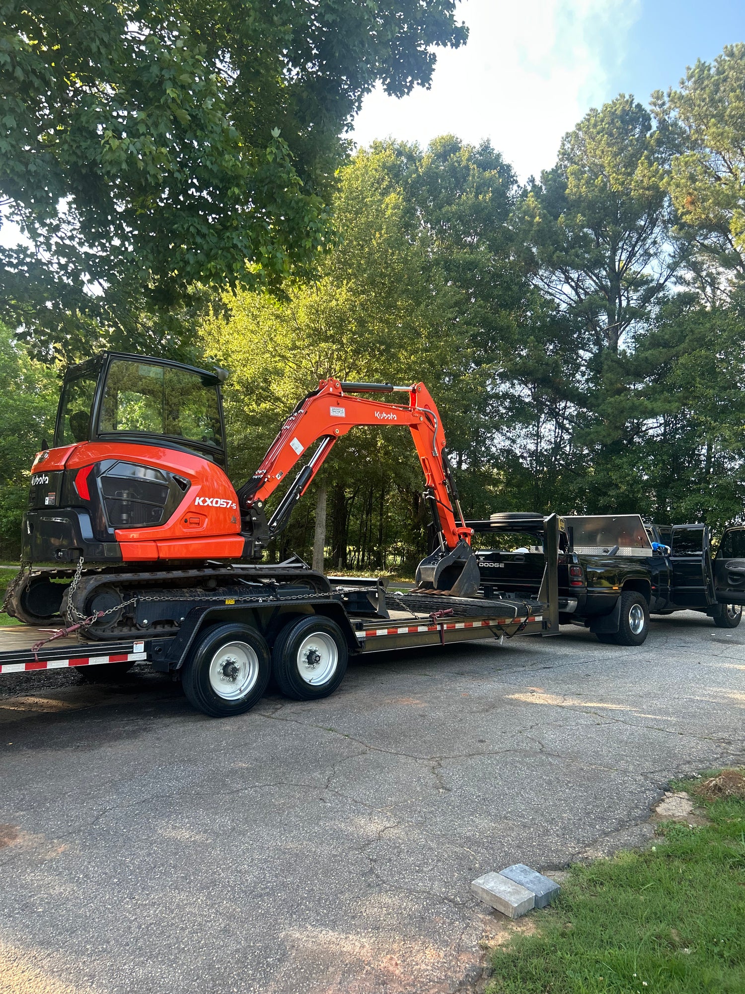 Orange excavator on a flatbed trailer with trees in the background